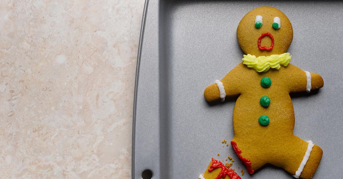 A broken gingerbread man looking shocked on a cooking sheet. 