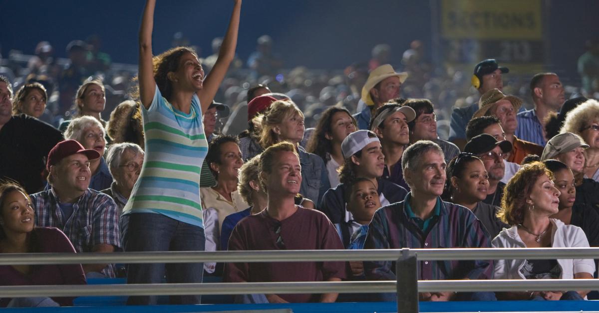 Fans cheering on a game from the stadium seats.