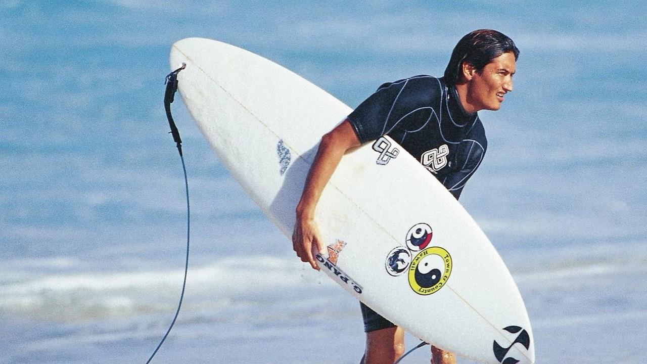 Mikala Jones with a surfboard on the beach