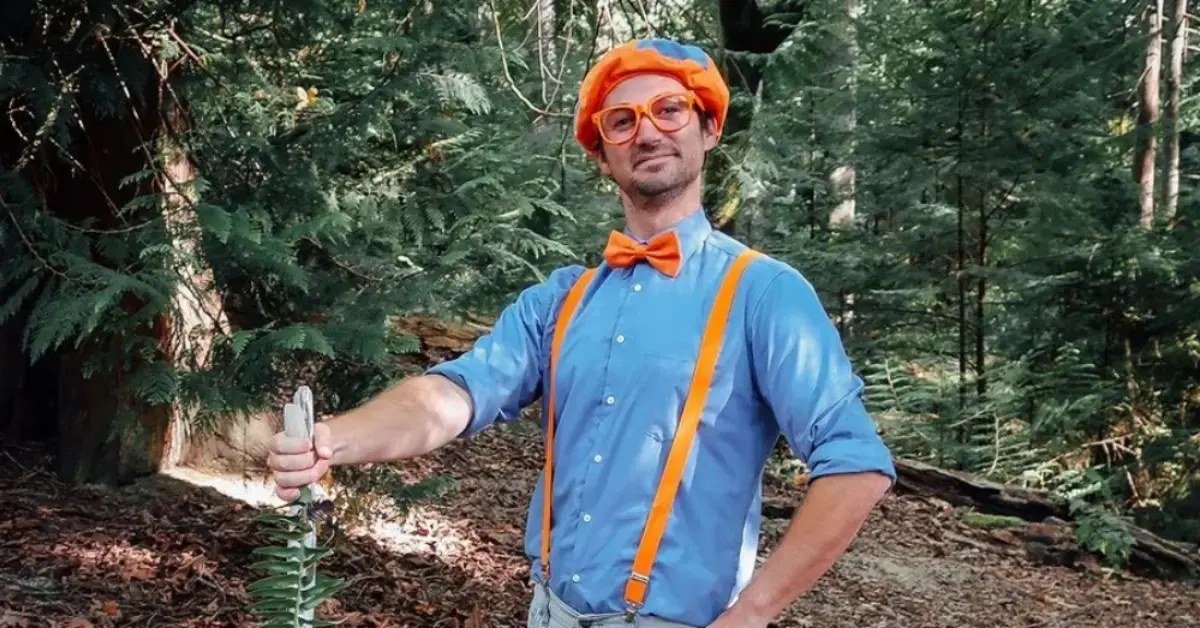 Blippi stands outside in the woods