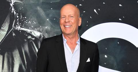 Bruce Willis wearing a black suit and blue shirt.