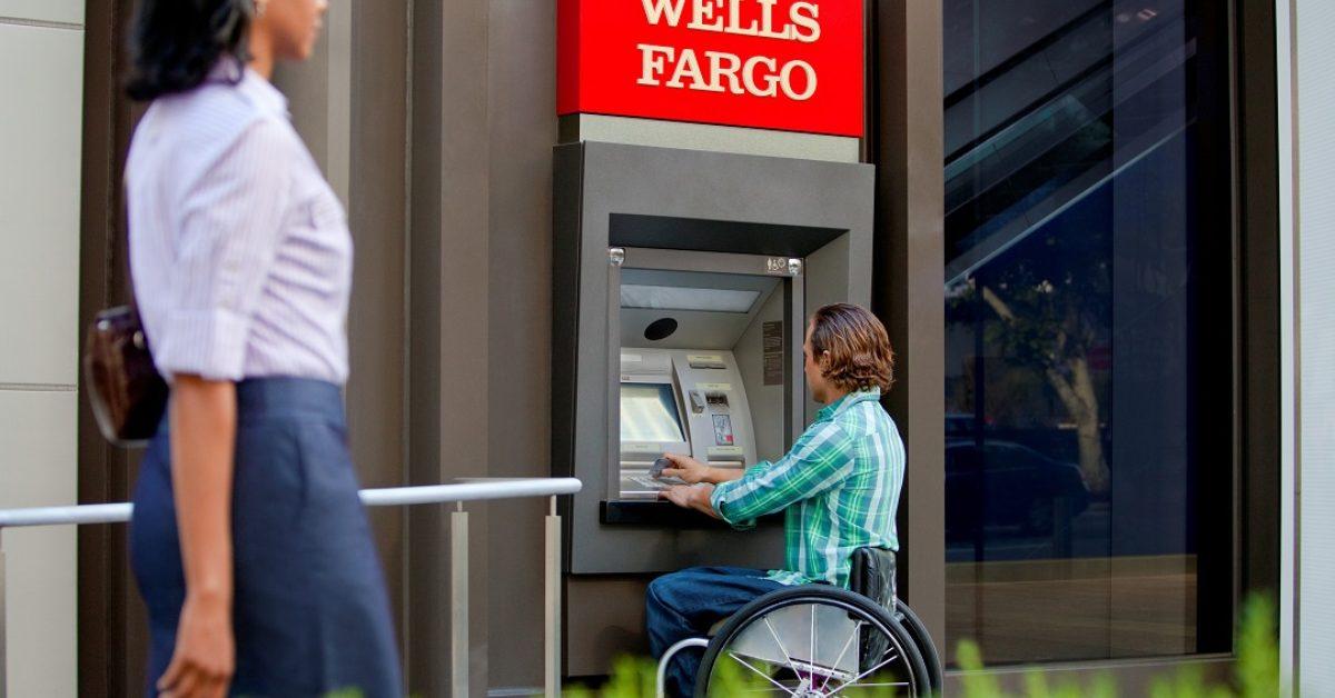 A man in a wheelchair using a Wells Fargo ATM.