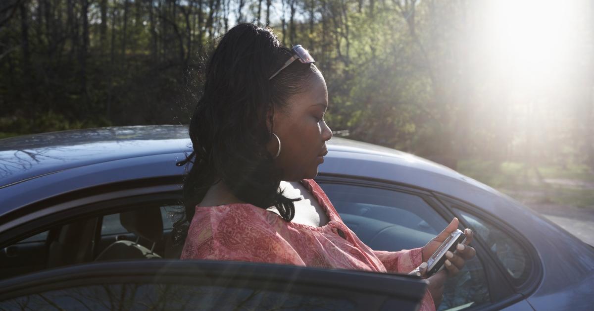 woman standing outside car checking phone