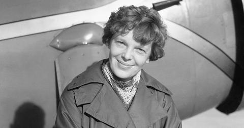Amelia Earhart sitting on a plane and smiling.