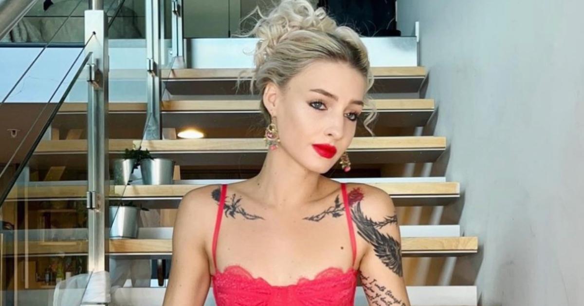 Moriah Plath showing off her tattoos sitting on the stairs.