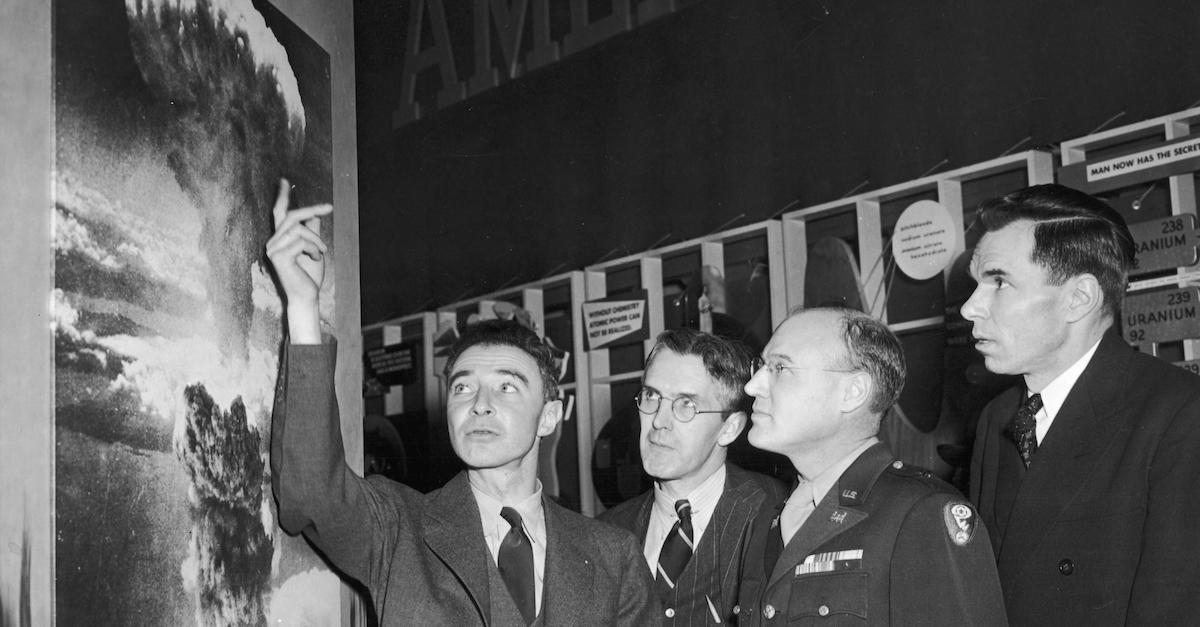 American physicist Dr. Robert Oppenheimer (1904 - 1967), points to a picture of the atomic bomb explosion over Nagasaki, Japan