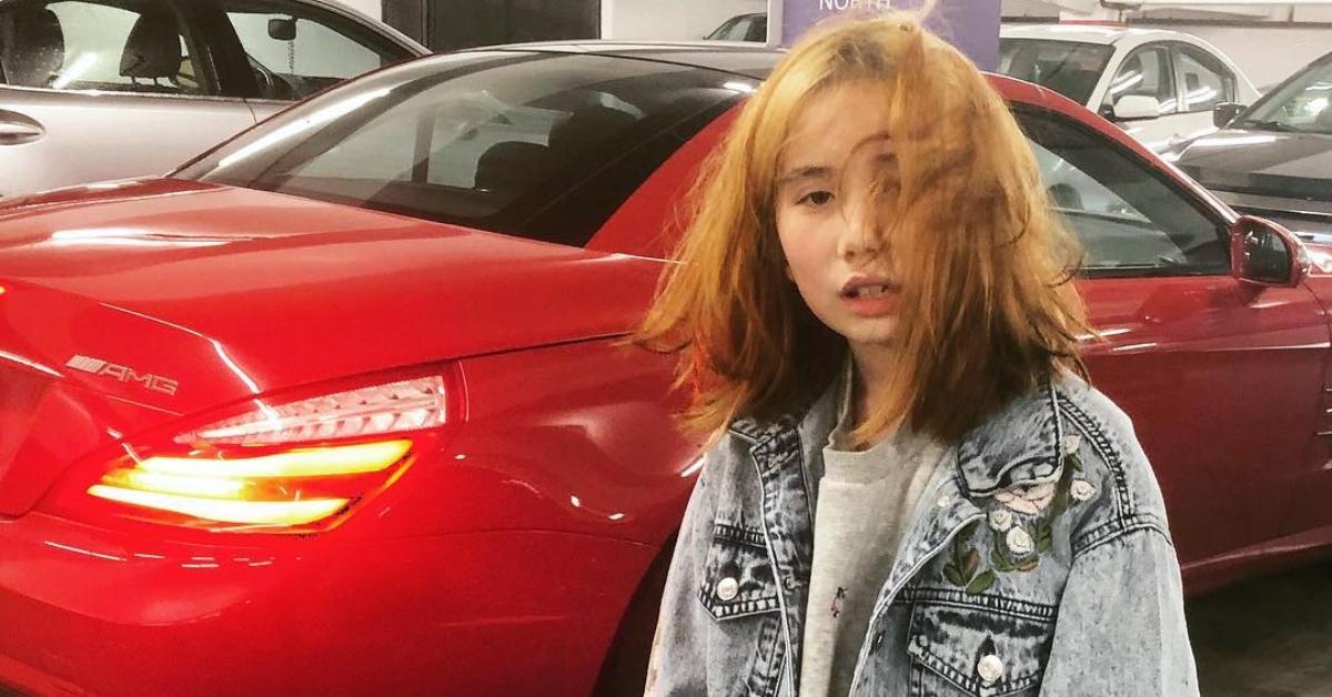 Lil Tay standing next to a red car