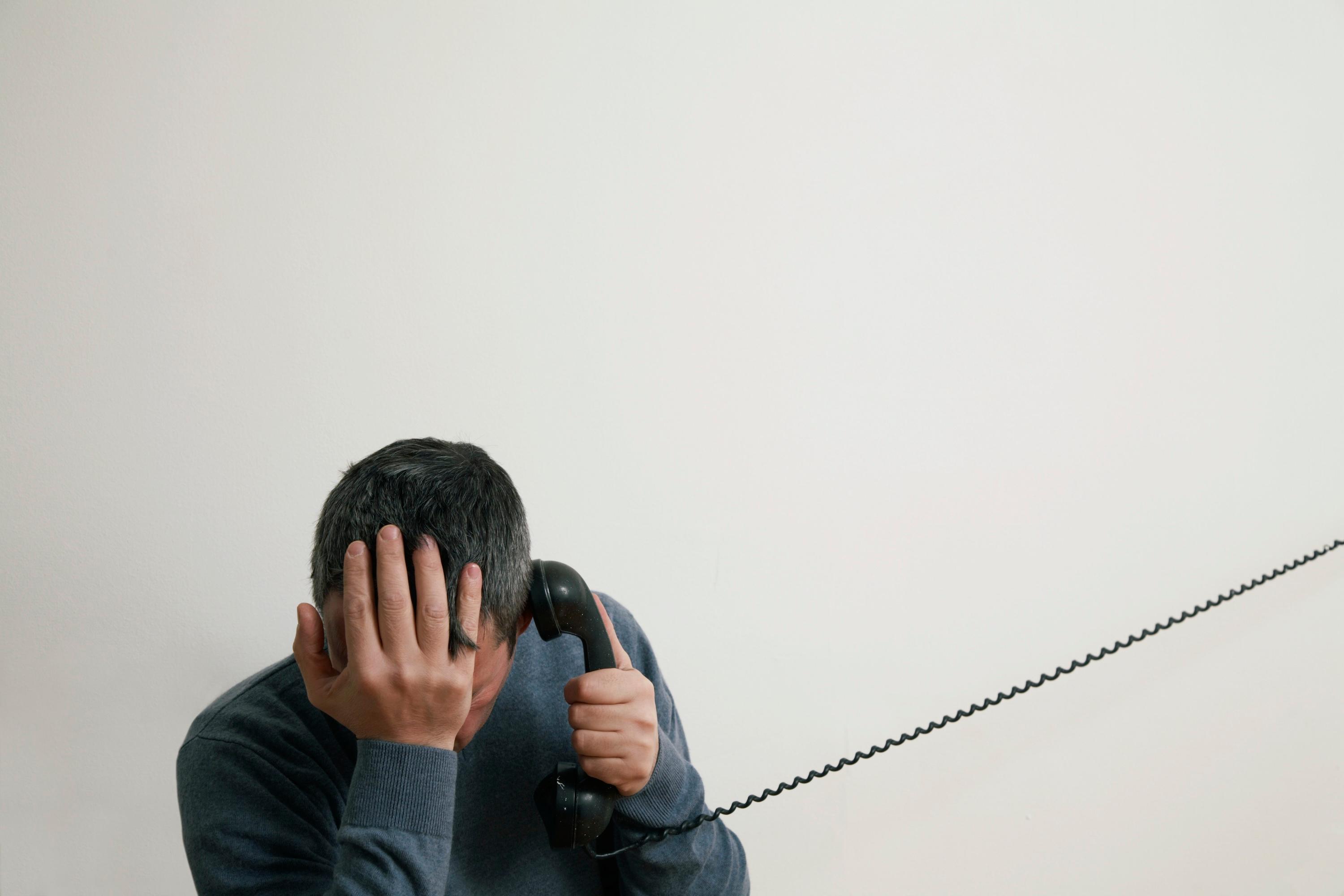Man sitting on stairs using telephone, hand to head