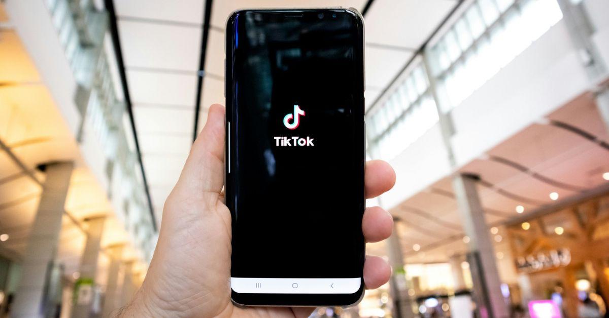 A person holding a phone in the air with TikTok app loaded on the screen.