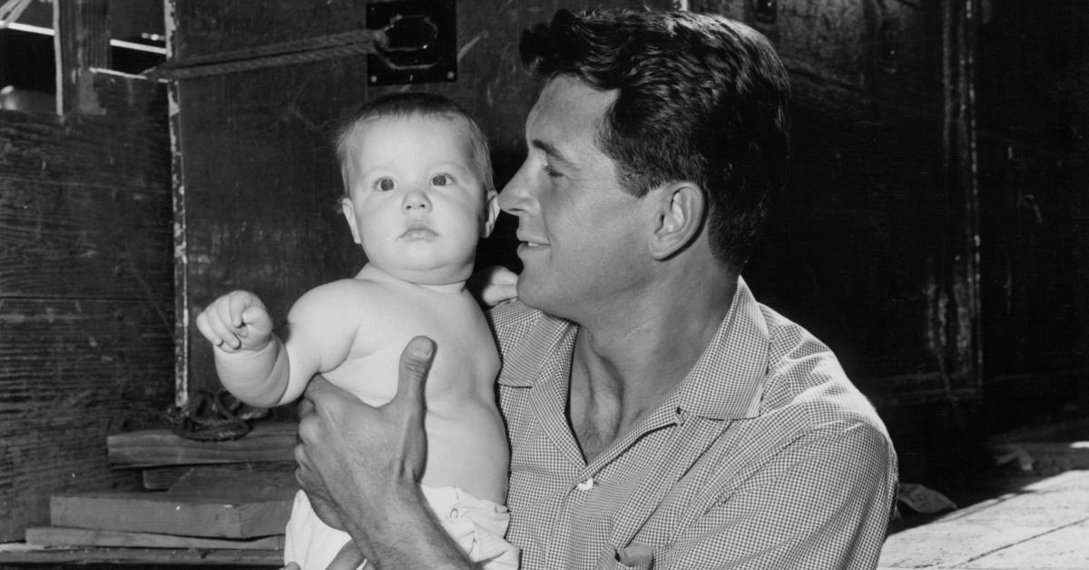 Rock Hudson holding a baby in a scene from the film 'This Earth Is Mine' in 1959.