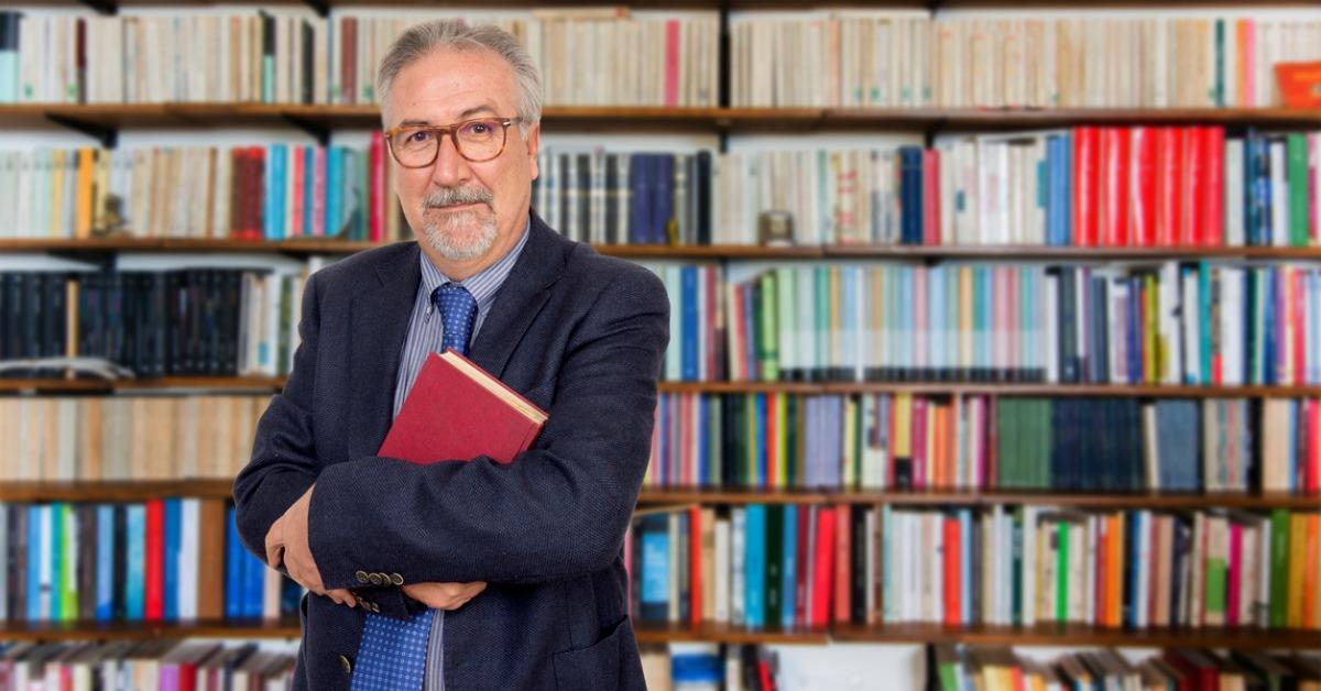 senior-teacher-standing-holding-a-book-in-front-of-a-bookcase-picture-id878473994-1537612706570-1537612708851.jpg