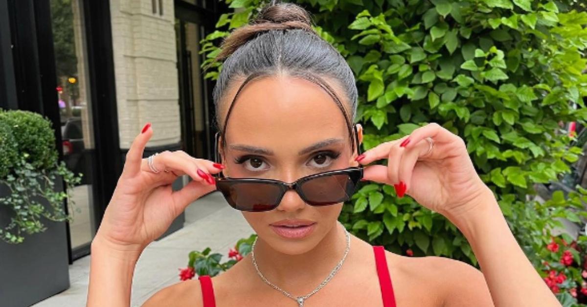 sofia franklyn with hair in bun, wearing sunglasses, red shirt and red nails