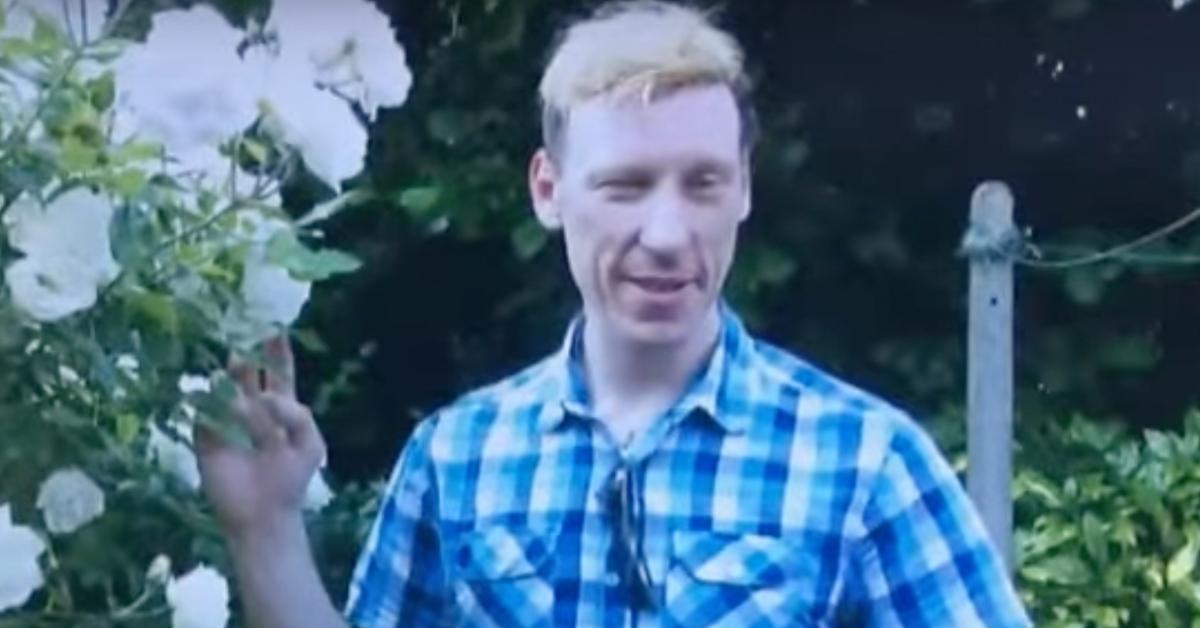 Stephen Port stands in front of a bush with flowers