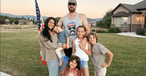 Meili Workman stands holding her youngest child next to her husband and three other kids