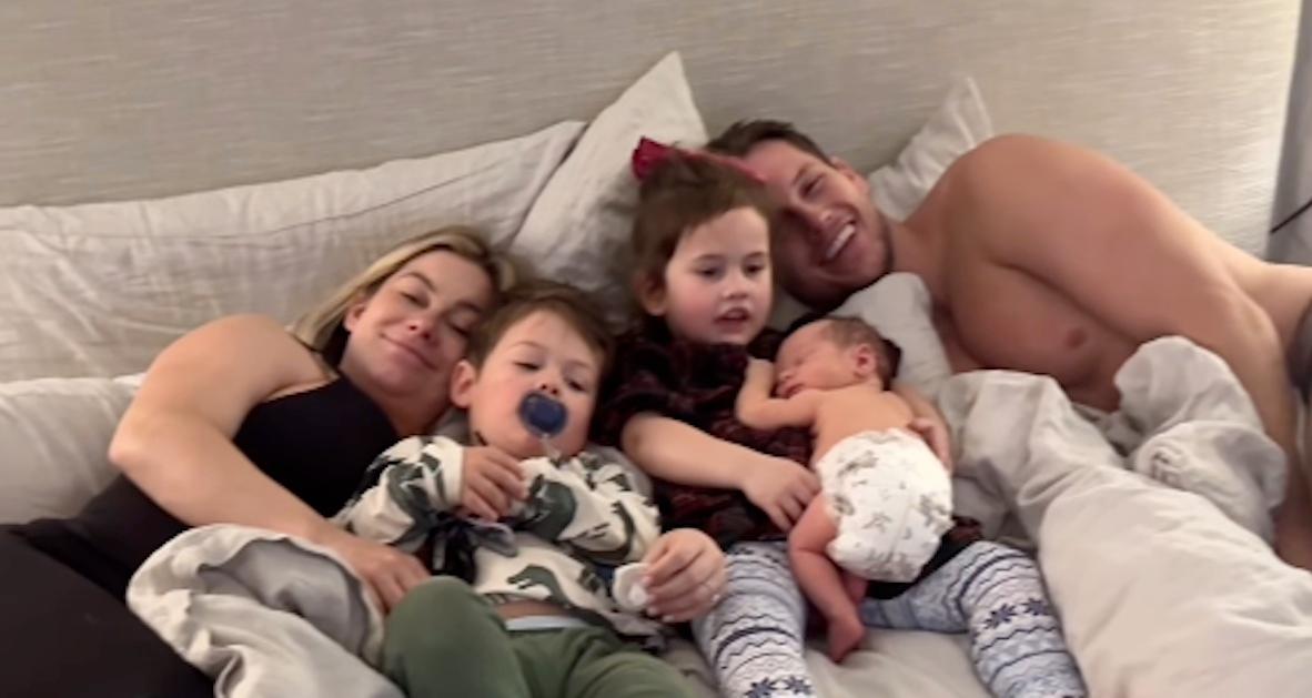 Shawn Johnston lying on a bed with her three kids and husband