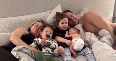 Shawn Johnston lying on a bed with her three kids and husband