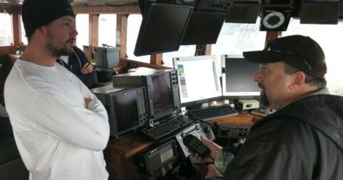 A crewman speaks with Tony Lara who is seated and holding the radio.