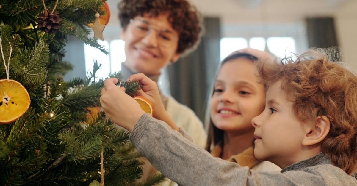 Kids adding ornaments to their Christmas tree.