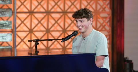 Benson Boone sitting at a piano with a microphone.