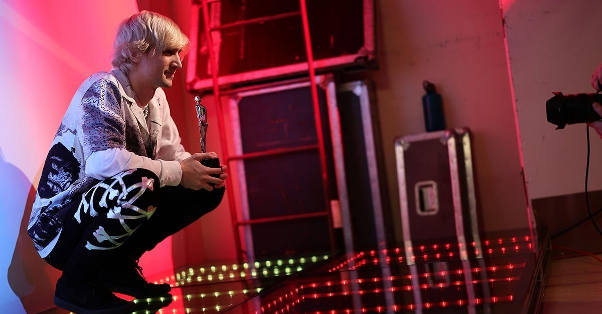 xQc holding a trophy backstage during an event.