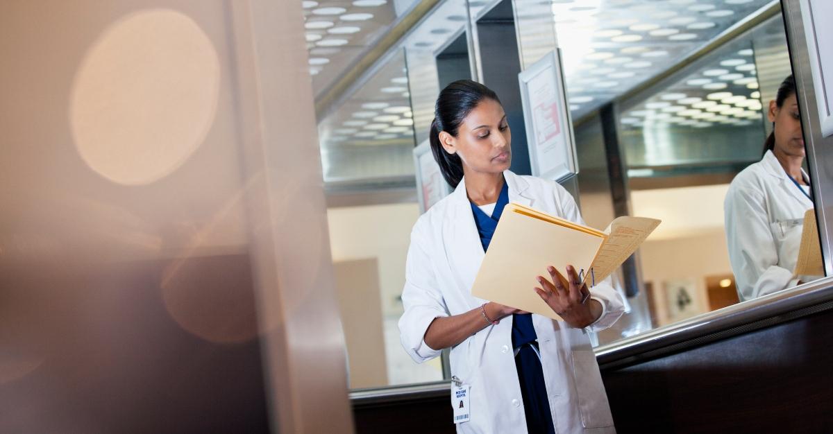 Doctor reviewing medical record in hospital elevator - stock photo