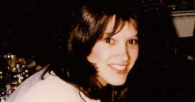 Joyce Hibbs smiles by a Christmas tree