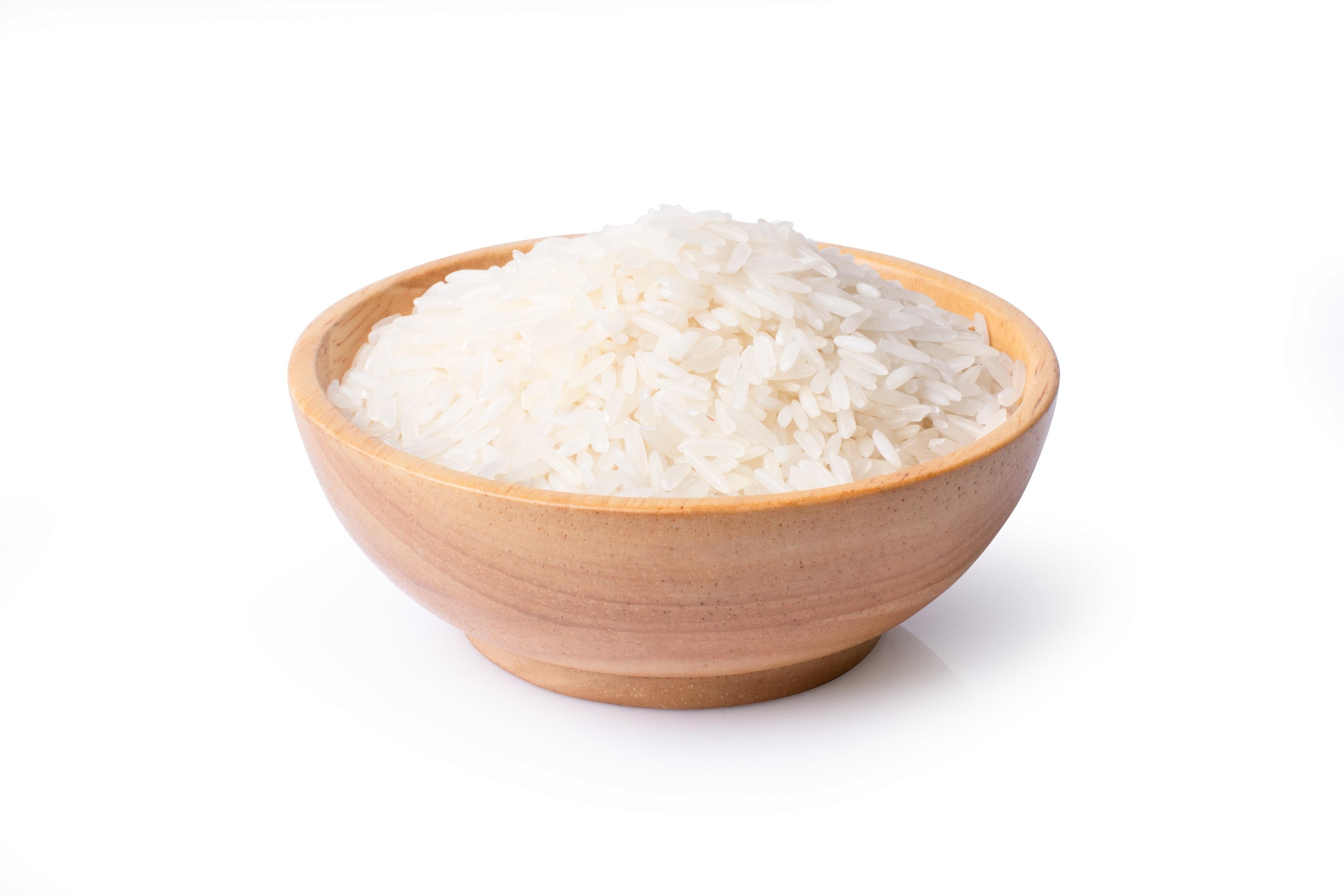 White uncooked long rice in wooden bowl isolated on white background with clipping path