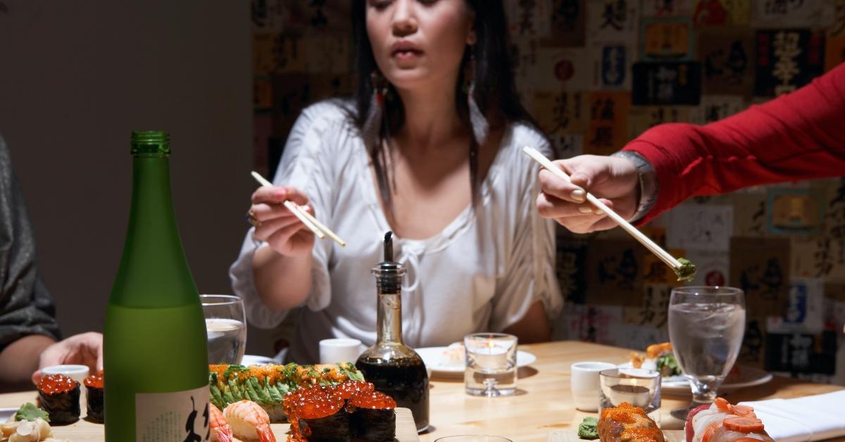 young women eating sushi in restaurant