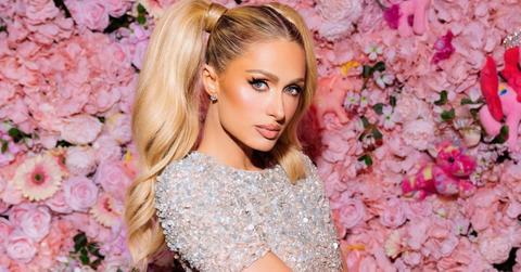 Paris Hilton in front of a wall of flowers