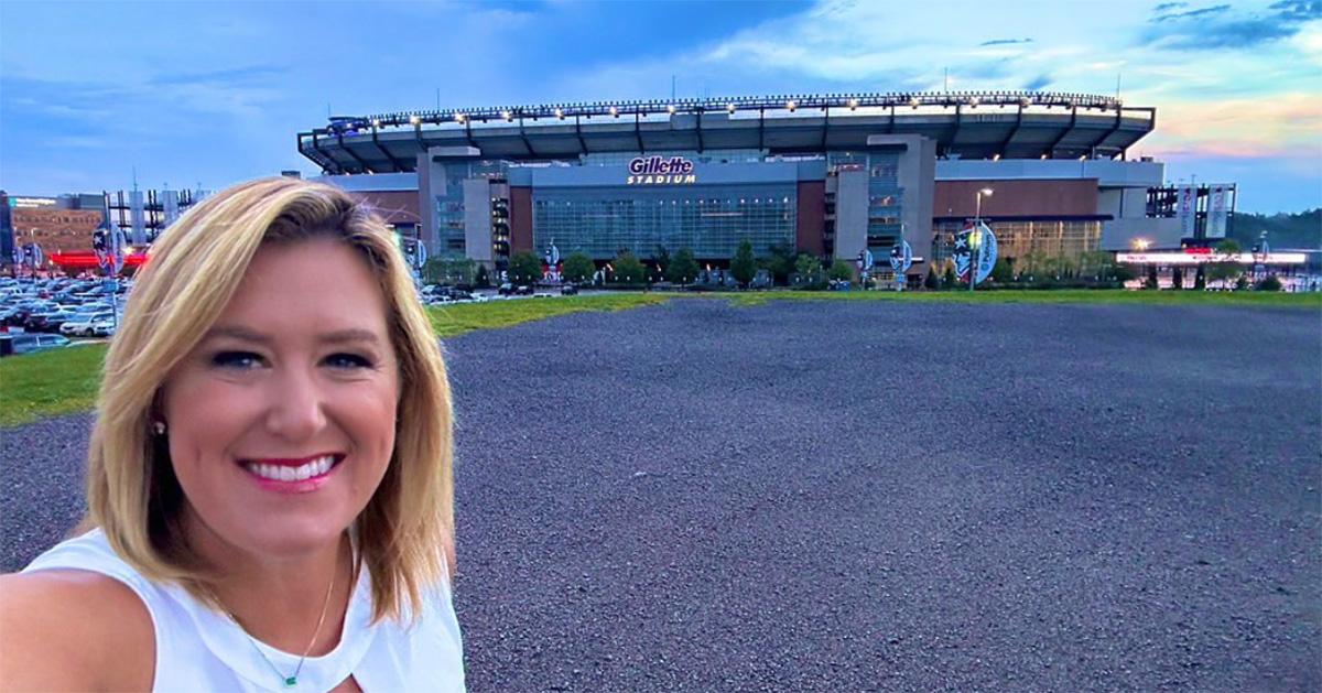 Jamie Apody in a white dress in front of Gillette Stadium. 