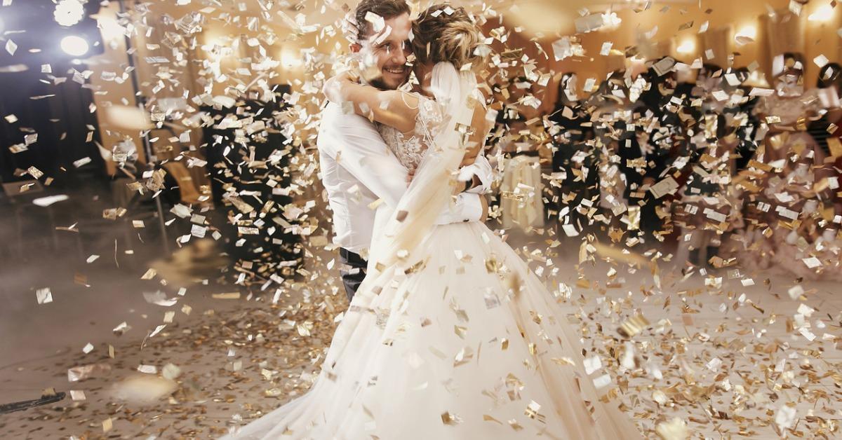 gorgeous bride and stylish groom dancing under golden confetti at picture id