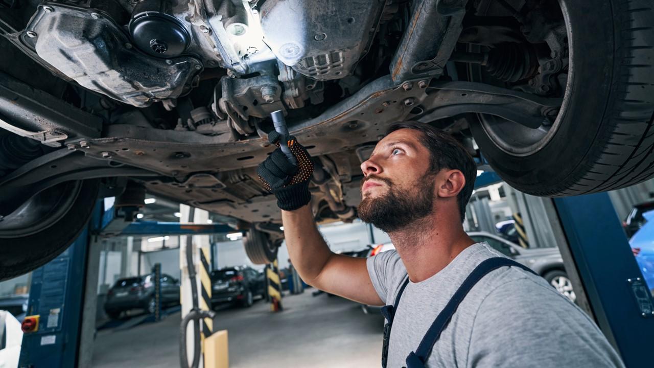 A mechanic using a flashlight or "torch" to look under a car