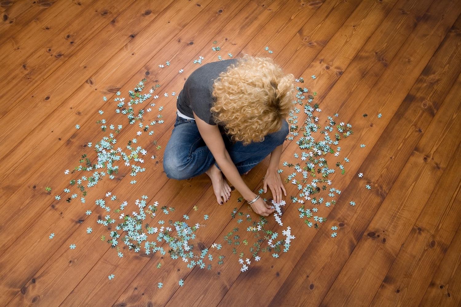 Woman building a puzzle on the floor.