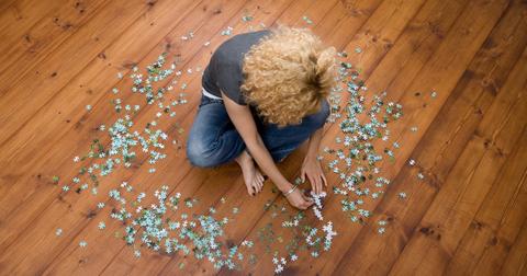 Woman building a puzzle on the floor.
