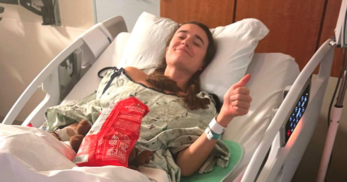 Kelley Mack in bed with her thumb up. 