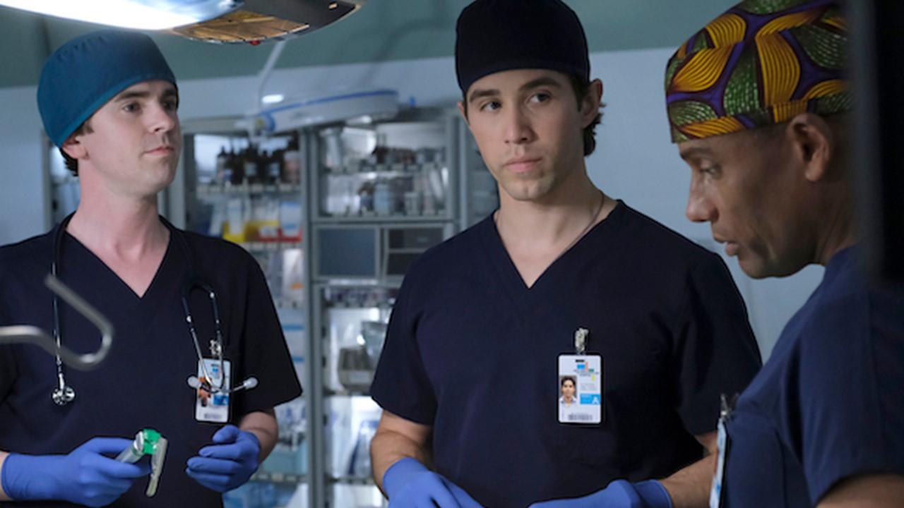 Dr. Danny Perez (C) wearing navy scrubs and talking to two other doctors on 'The Good Doctor'