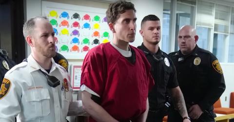 Bryan Kohberger standing handcuffed next to law enforcement officers