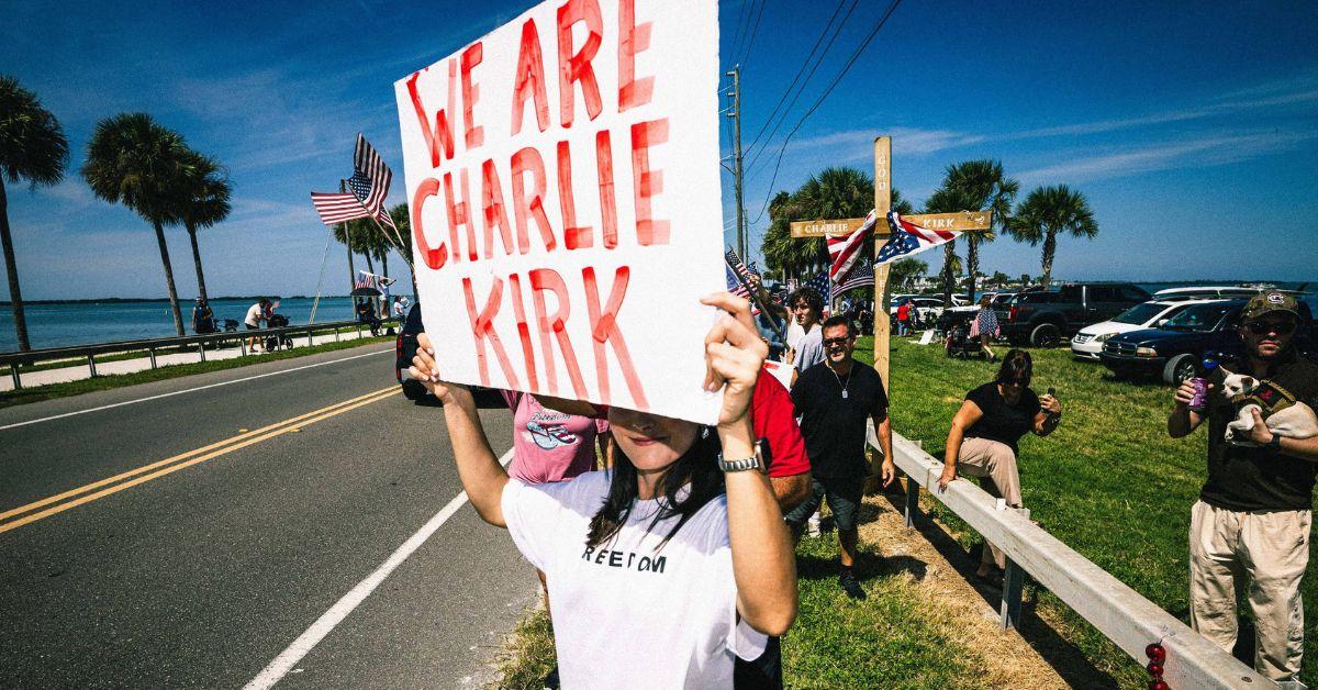 A woman holding a sign that says "We Are Charlie Kirk."