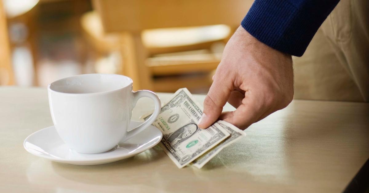 Man leaving tip on table at cafe for cup of coffee