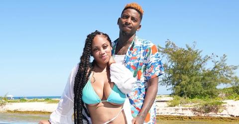 Jaliyah Monet wears a blue swimsuit and FunnyMike stands behind her on a boat near an island.