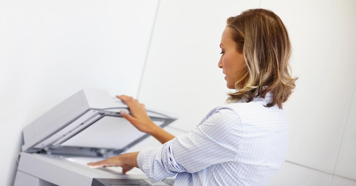 A woman putting a piece of paper in a copier. 