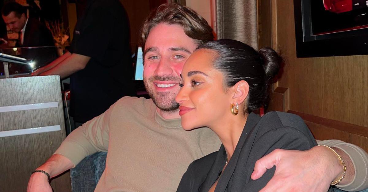 Greg Grippo and Victoria Fuller smile and hold each other close while out to eat at a restaurant.