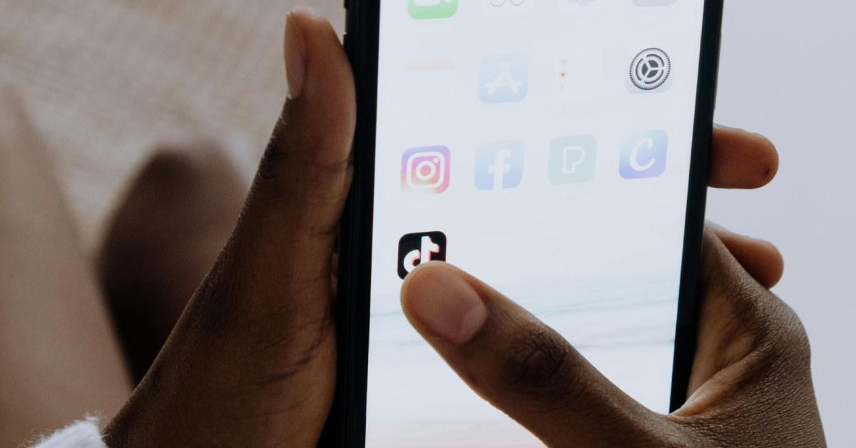 A hand tapping the TikTok app on a smart phone.