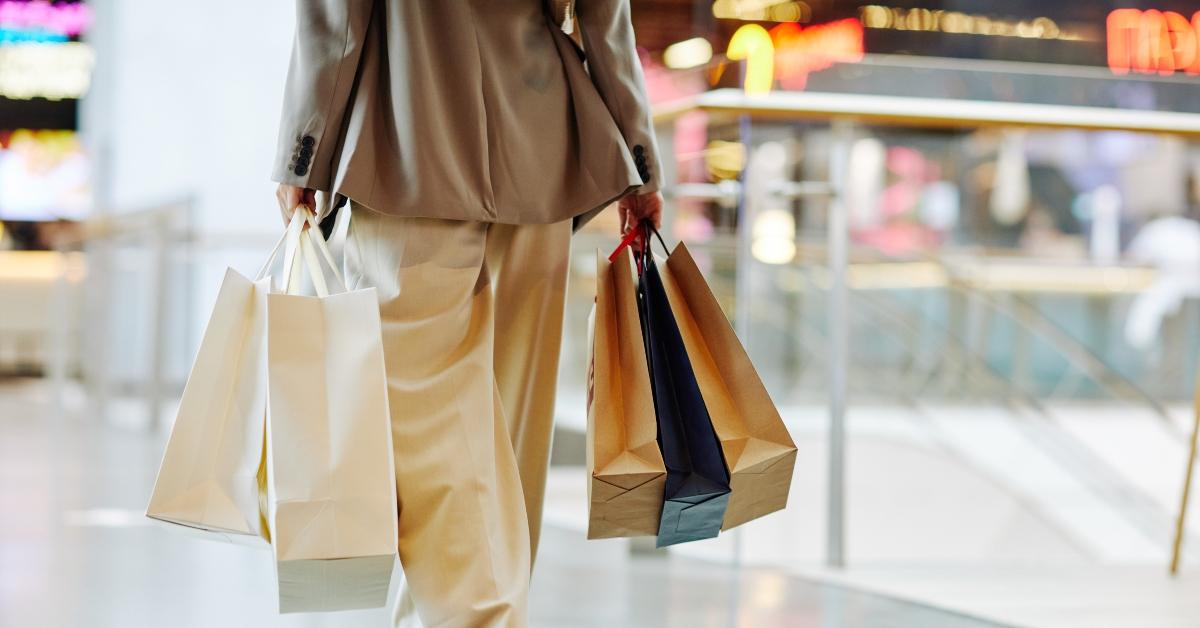 woman walks with shopping bags in mall, seen from behind