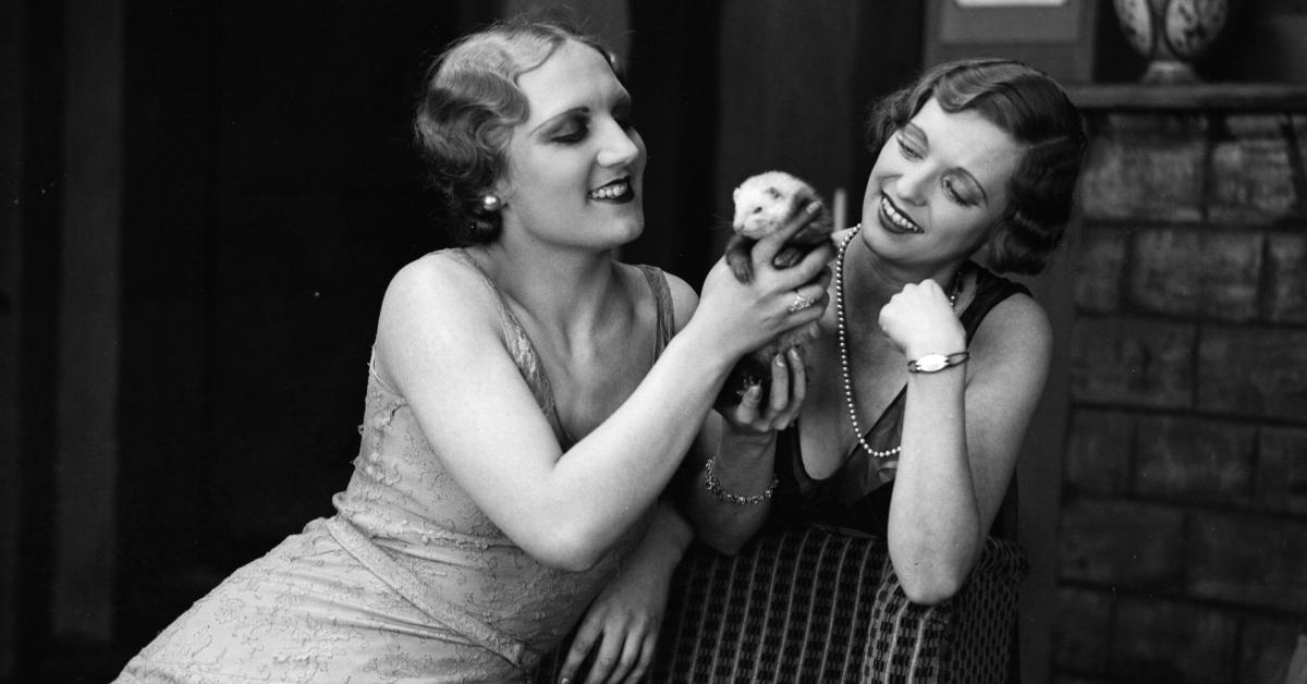 Two women hold a ferret