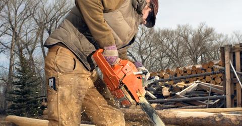 man using chainsaw to cut a log