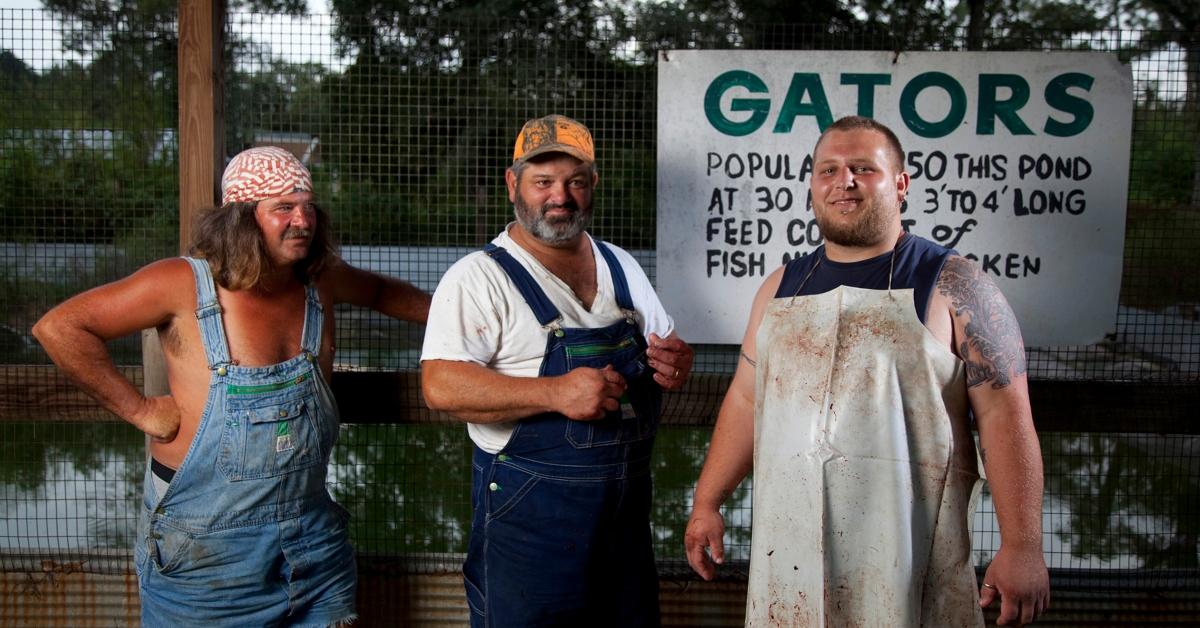 Swamp People cast members stand against a fence