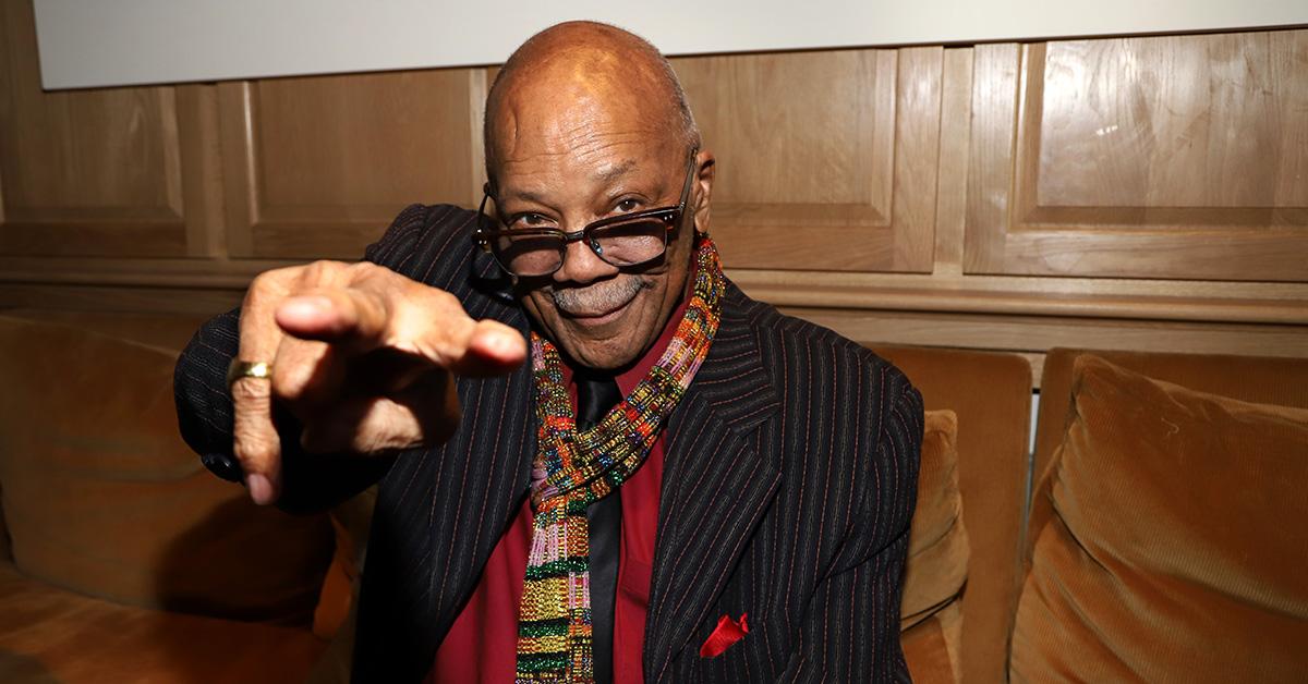 Quincy Jones pointing while sitting on a couch. 