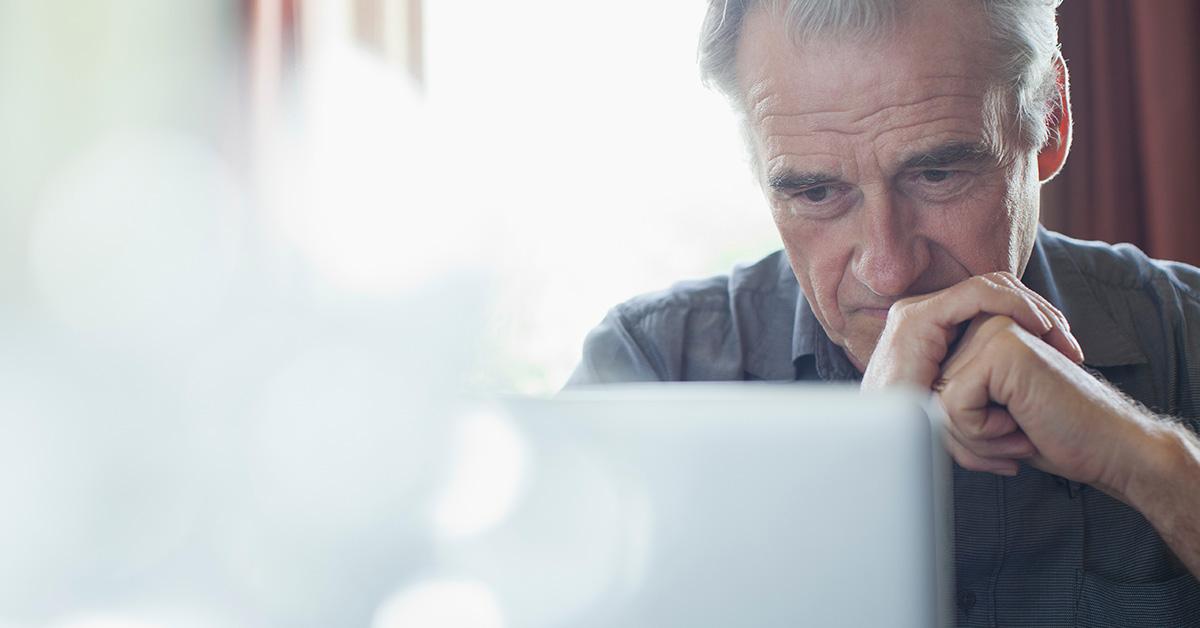 Older man looking frustrated while working on a computer.