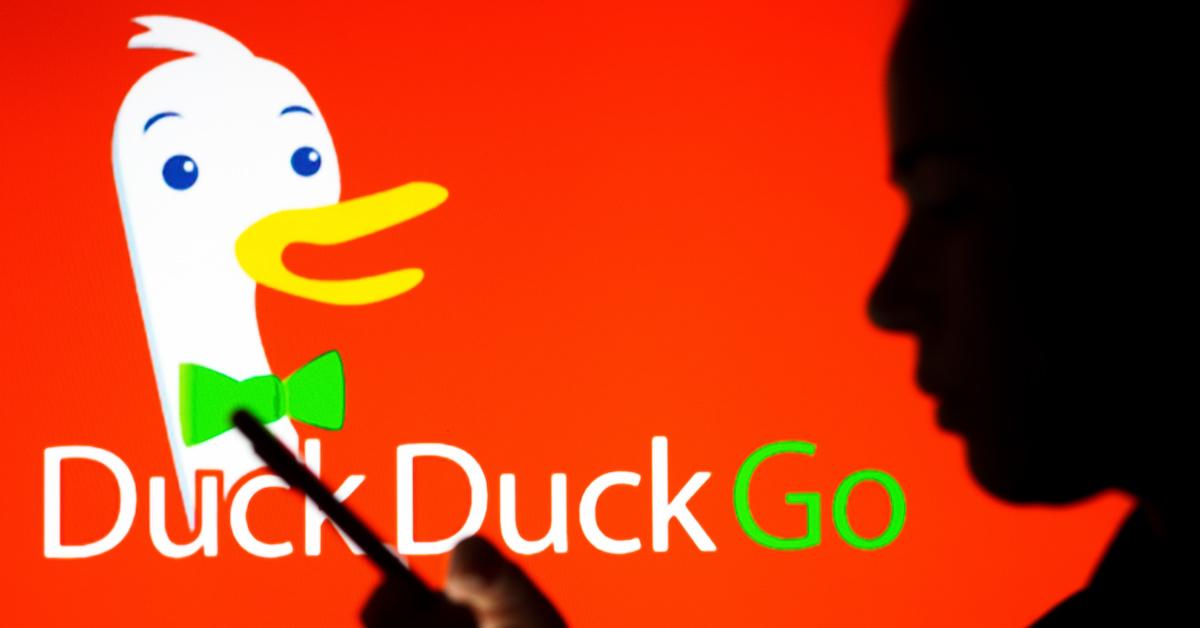 A person looking at smartphone with DuckDuckGo logo in the backdrop